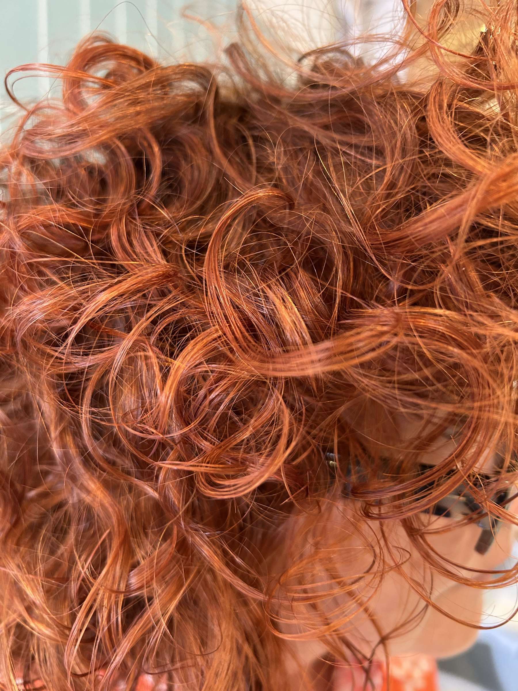 Rizos cobrizos definidos con método curly, vistos de cerca